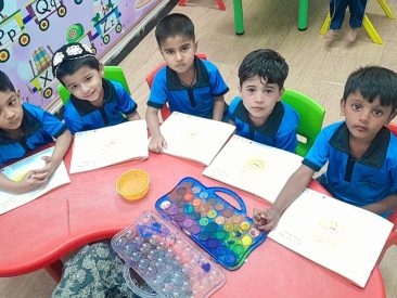 Children in Stepping Stone uniforms painting with watercolours at a classroom table