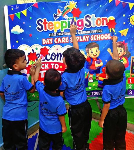 Children sticking paper stars on the Stepping Stone welcome back to school banner